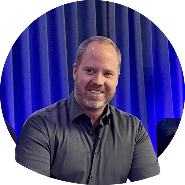 Andreas smilende i grøn skjorte, mellemblondt hår og kort skæg. Foto.