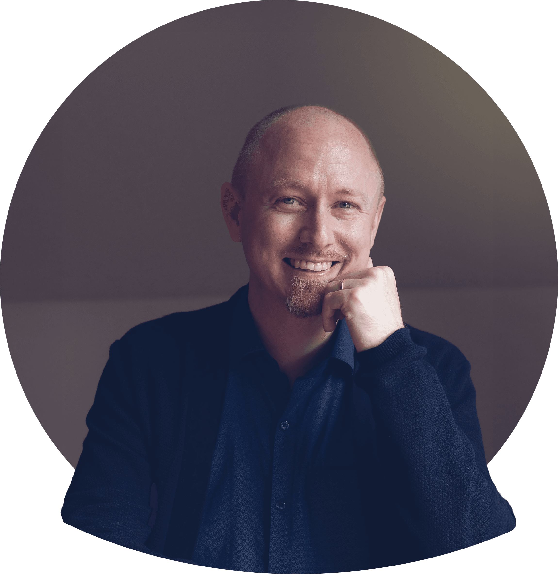 Danne med kort blondt hår og skæg i mørk jakke og lys t-shirt, smilende. Foto.