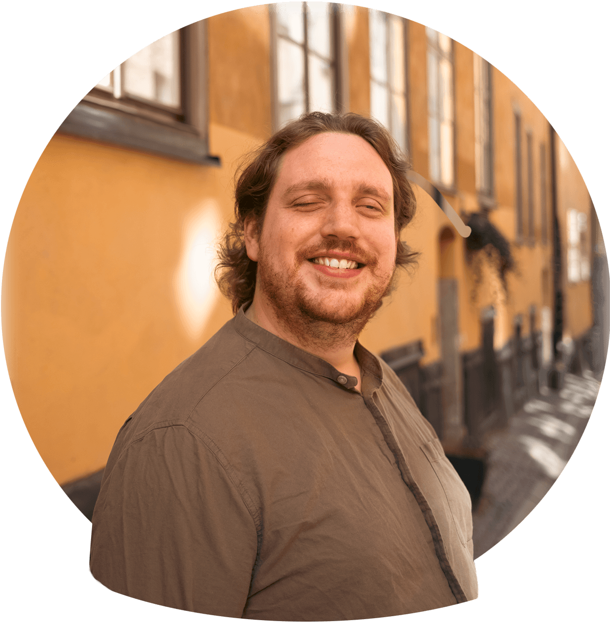 Christoffer er en mørkhåret mand med et stort smil, lidt ansigtsbehåring og en brun skjorte. Foto.