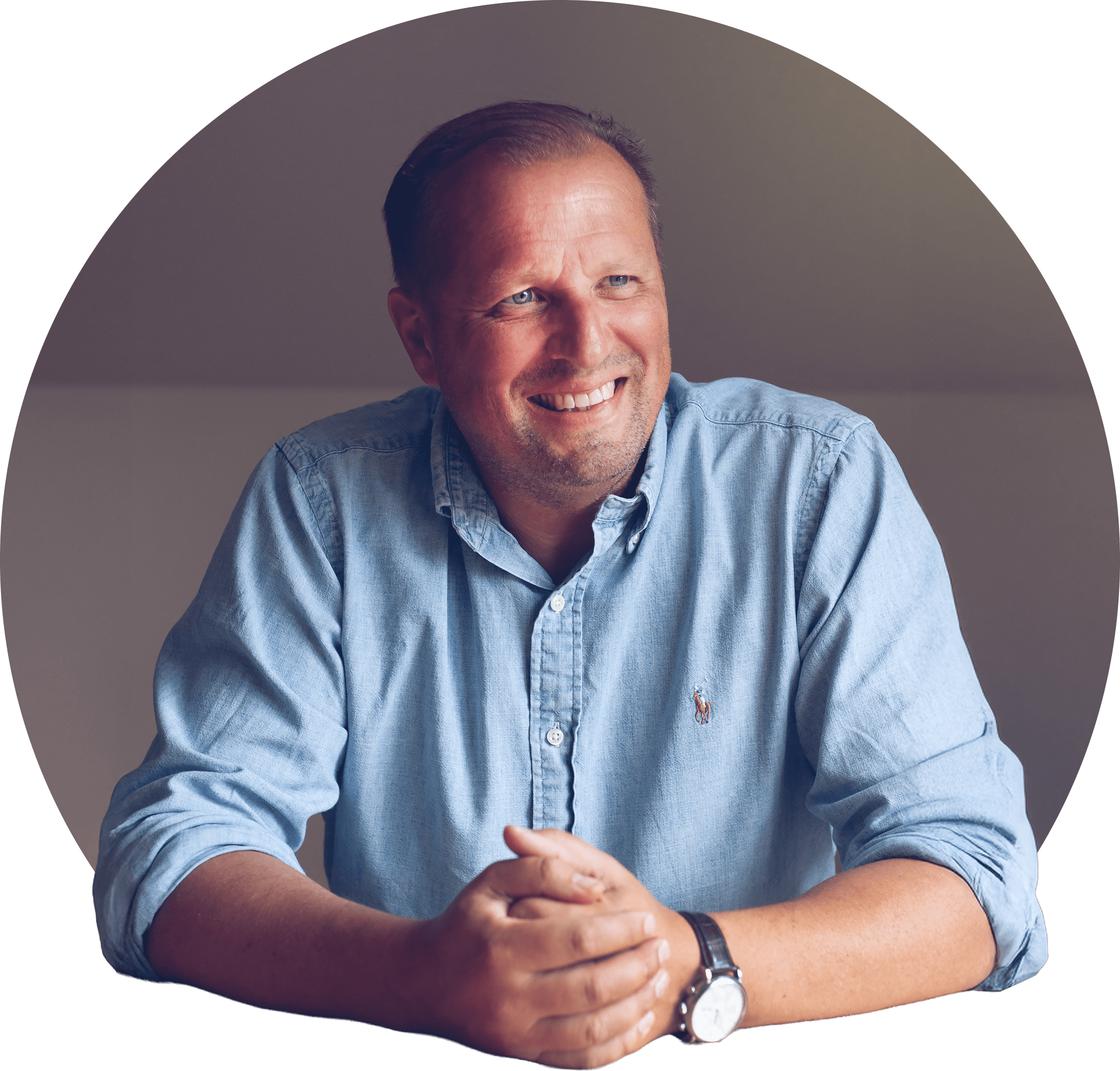 Fredrik smilende med smilehuller, brun kort frisure i lys skjorte. Foto.